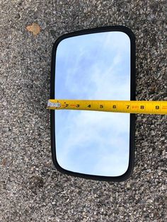 there is a measuring tape on the ground next to a car mirror