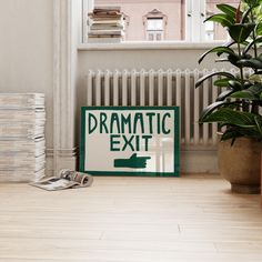 a green and white sign sitting on top of a wooden floor next to a potted plant