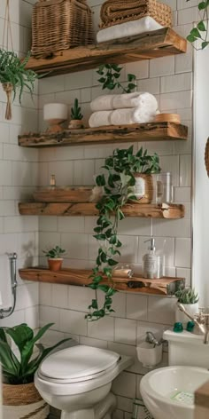 the bathroom is decorated in white and has wooden shelves above the toilet, along with greenery