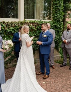 the bride and groom are exchanging vows at their wedding ceremony in front of an ivy covered building