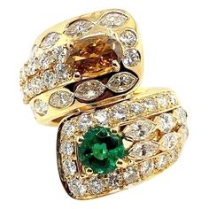 Retro 18k Yellow Gold GIA Certified 7.4 Approximate Carat Natural Emerald & Diamond Cocktail Ring 1960. The Ring is with two Natural GIA Certified gems. The first is a natural 1.01 carat oval brilliant Fancy Deep Brownish Orangy Yellow (GIA#2205417222) measuring 8.54x5.80x2.77mm. The second is a natural 1.33 carat round brilliant green emerald (GIA#5171348815) measuring 6.62-6.81x5.06mm. In addition, the ring is set with approximately 5.06 carats of natural diamonds consisting of 32 G-H color (a Luxury Gia Certified Green Cluster Ring, Vintage Gia Certified Gold Emerald Ring, Luxury Vintage Emerald-cut Cluster Ring, Vintage Multi-stone Emerald Ring In 14k Gold, 1960s Cocktail Rings, Diamond Cocktail Ring, Jaune Orange, Diamond Cocktail Rings, Marquise Diamond