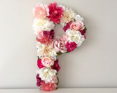 the letter p is made up of pink, white and red flowers on a table