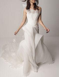 a woman in a white wedding dress is posing for a photo with her hair blowing in the wind