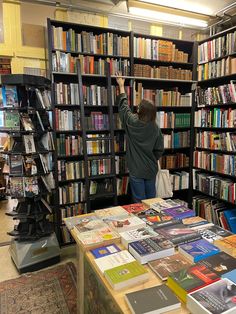 a person reaching up to reach for books in a book store with shelves full of books