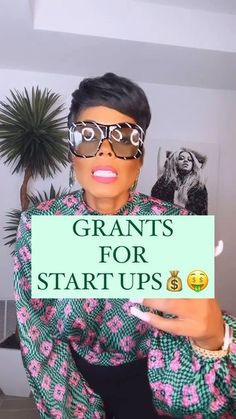 a woman holding up a sign that says grant's for start ups