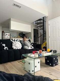 a woman sitting on a couch in a living room with black and white decor around her