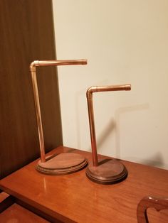 two metal candlesticks sitting on top of a wooden table