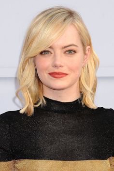 a woman with blonde hair wearing a black top and orange lipstick on her lips is looking at the camera