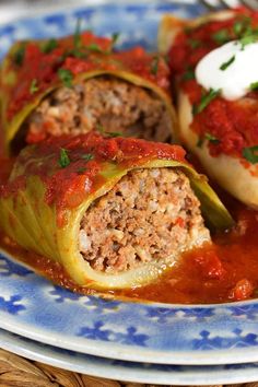 two stuffed cabbages on a blue and white plate with sauce, sour cream and parsley