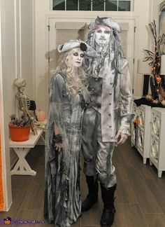 two people dressed in costumes standing next to each other on a wooden floor with halloween decorations behind them