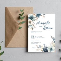 a wedding card and envelope with blue flowers on the front, sitting next to a brown envelope