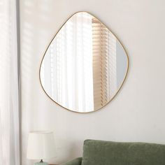 a living room with a green couch and a round mirror on the wall