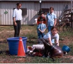 a group of people standing next to each other in a field near a fenced in area