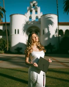 a beautiful young woman holding a folder in front of a large white building with palm trees