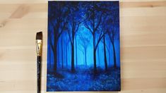 an acrylic painting of a blue forest with trees in the foreground and a paintbrush next to it