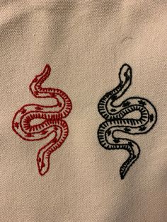 two red and black snake embroidered on white fabric, each with an individual's name