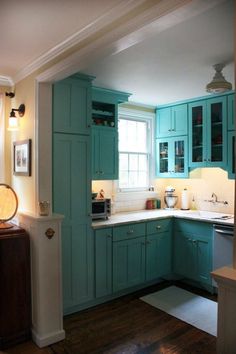 a kitchen with blue cabinets and white counter tops is pictured in this image from the doorway