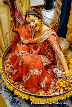 a woman sitting on top of a bed of flowers covered in yellow and red paint