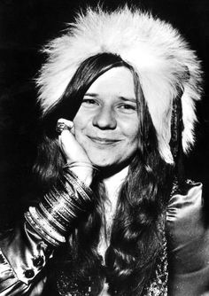 a woman with long hair wearing a fur hat and holding her hand to her face