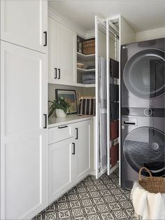 a washer and dryer in a white laundry room with black tile flooring