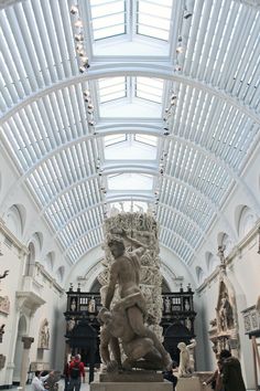 the inside of a museum with sculptures and people