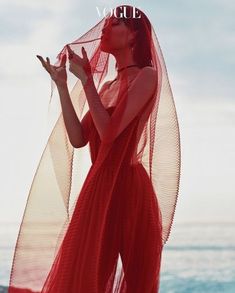 a woman in a red dress standing on the beach