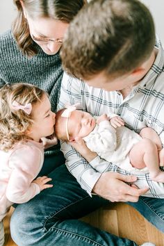 a man and woman holding a baby while sitting next to each other on the floor