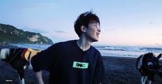 a young man standing on top of a sandy beach next to the ocean