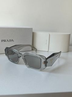 Brand new Prada PR17WS 12R30B Sunglasses in Transparent Clear.Featuring a clear acetate frame with light grey lenses.Gold metal Prada logos on temples.Size 49-20-145.100% authentic and unworn.Made in Italy.Box, case, cloth and paperwork included. Designer Clear Sunglasses With Polarized Lenses, Luxury Clear Sunglasses With Uva Protection, Designer Clear Glass Sunglasses, Prada 17ws, Prada Pr17ws, Pretty Sunglasses, Prada Glasses, Trendy Glasses, Fashion Eye Glasses