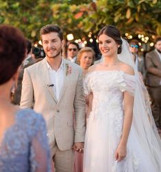 a bride and groom walking down the aisle at their outdoor wedding ceremony with guests in the background