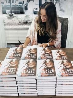 a woman sitting at a table in front of stacks of books with the words pray your self written on them