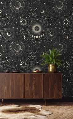 a black and white wallpaper with stars and moon designs on it, next to a wooden cabinet