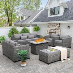 an outdoor living room with grey wicker furniture and a fire pit in the middle