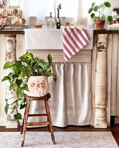 a potted plant sitting on top of a wooden stool in front of a sink