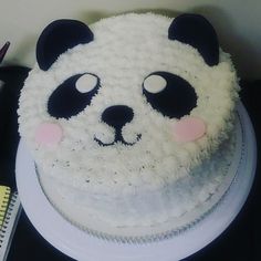 a panda bear cake sitting on top of a white plate next to a notebook and pen