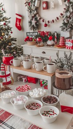 a table topped with lots of bowls filled with candy and marshmallows next to a christmas tree