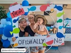 a man and woman holding a baby in front of a sign that says tatum offishally one