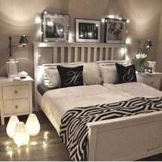 a white bed topped with lots of pillows next to two night stands filled with lights