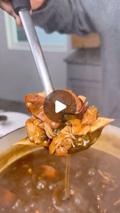 a spoon full of food being held up by someone's hand with a ladle