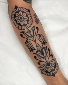 a black and white tattoo on the leg of a person's arm with flowers