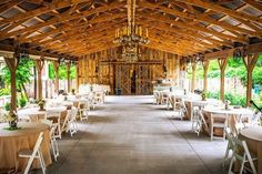 the inside of a barn with tables and chairs set up for a formal function,