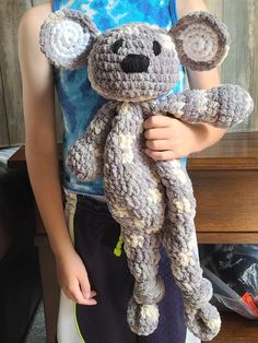 a young boy holding a crocheted koala bear