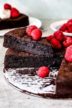 two slices of chocolate cake with raspberries on the top and one slice missing