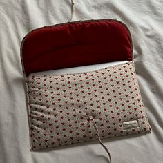 an open red and white bag sitting on top of a bed next to a pillow