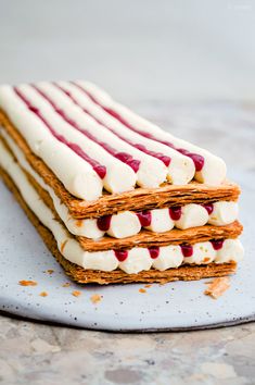 three desserts stacked on top of each other with white frosting and raspberries