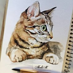 a drawing of a cat with green eyes on a notepad next to a pen