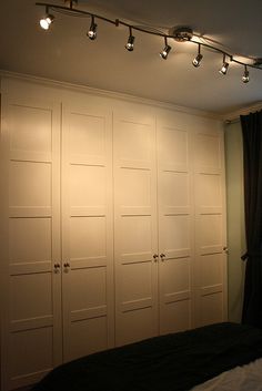 a bedroom with white closets and lights on the ceiling