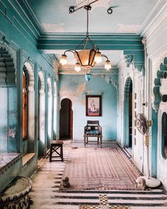 an ornate hallway with blue walls and rugs on the floor in front of a bench