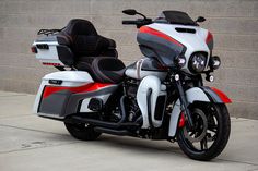 a white and red motorcycle parked in front of a brick wall with a black seat