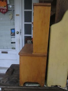 an old wooden cabinet sitting on top of a table next to a yellow refrigerator freezer